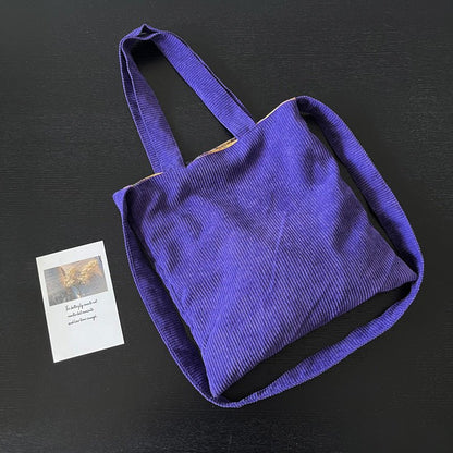 Purple corduroy tote bag with soft textured fabric, spacious interior, durable stitching, for daily use, commuting & travel.